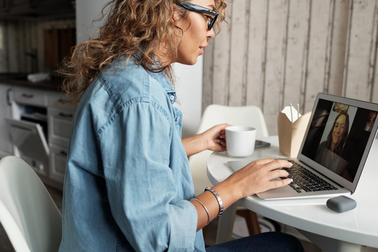 Woman in blue shirt having video call on laptop